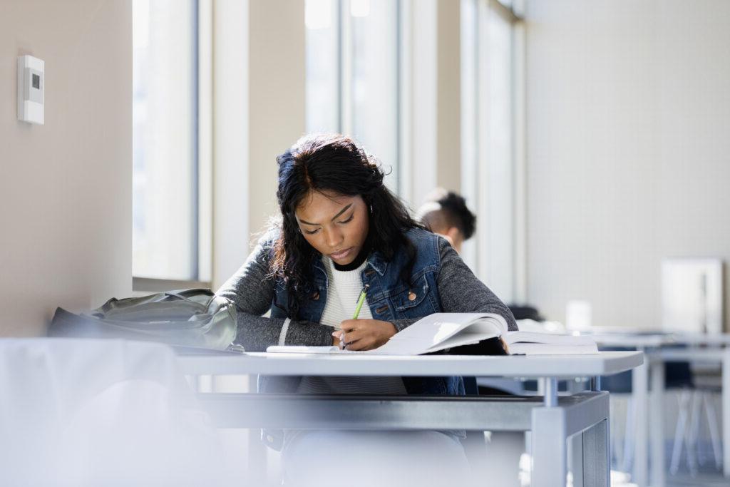 The young woman is focused on 阅读 through her textbook.